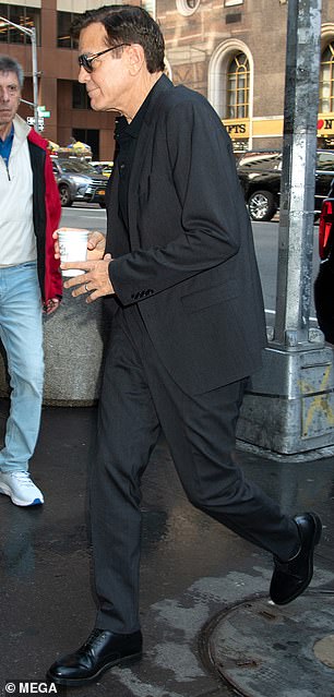 Он прибыл на площадку в характерном для него элегантном костюме угольного цвета в сочетании с черной рубашкой-поло, кожаными туфлями и тенями.